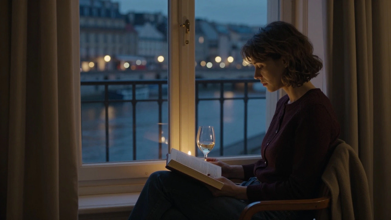 A woman sits by a window in a quiet Paris apartment, lit by candlelight, gazing at the Seine at night.